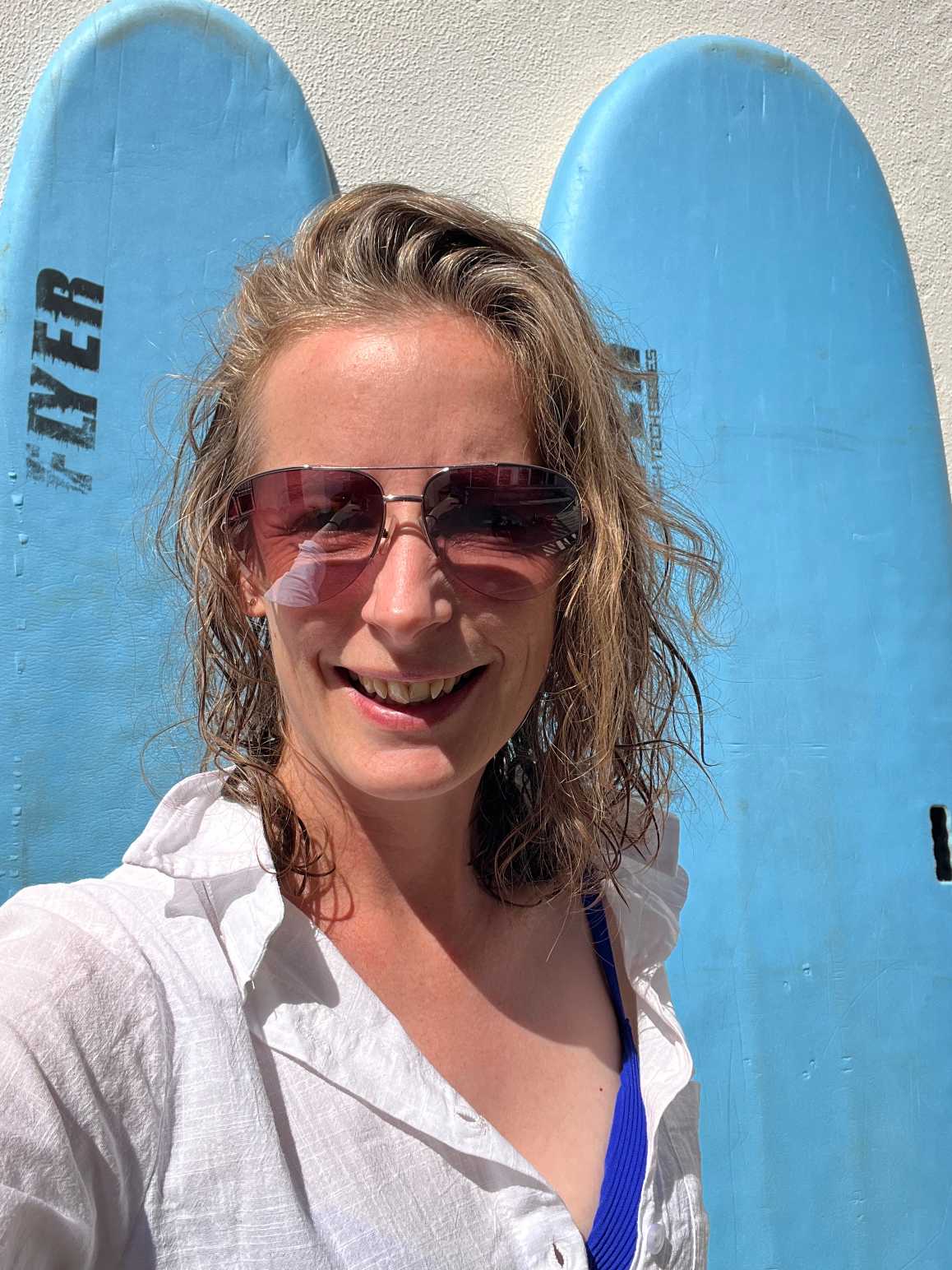 Stacey in sunglasses by surfboards