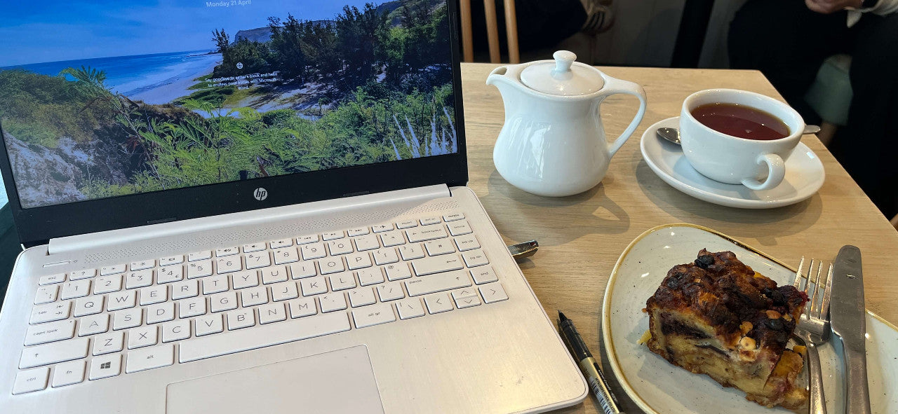 a laptop, with tea and cake
