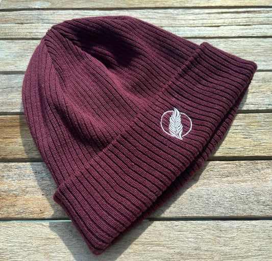 Roho Rafiki® embroidered icon organic cotton beanie. Crafted from 100% organically-sourced Control Union Certified cotton, this lightweight design in a heritage-inspired fine rib is the perfect all-year-round option for casual headwear. Embroidered with the white feather icon logo. A range of colours are available. Burgundy.
